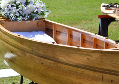 A wooden canoe coffin with white flowers on top
