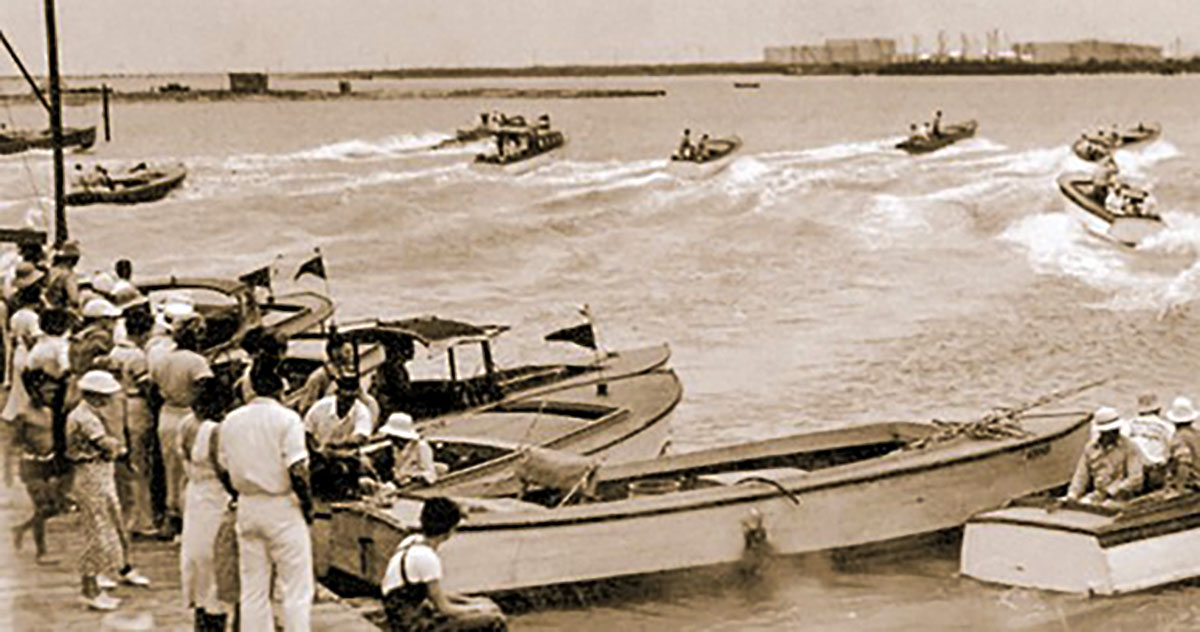 Vintage photo of a fishing rodeo with several boats in the water and some on shore.