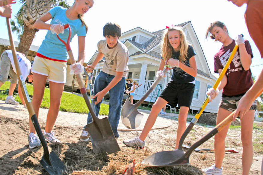 A group of kids dig with shovels in front of the Port Aransas Museum