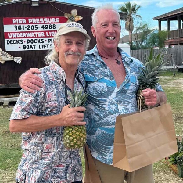 Cliff Strain holding a pineapple and another man holding a paper bag